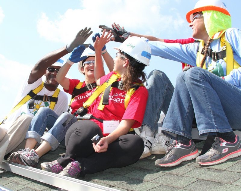 Construction workers in safety gear celebrating together on a rooftop