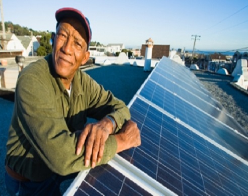 Lawrence Jackson sits on his roof, leaning on his solar panels