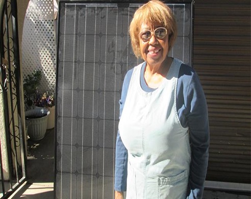 Marguerite Crowell smiling outdoors wearing glasses, a white vest, and blue long-sleeved shirt