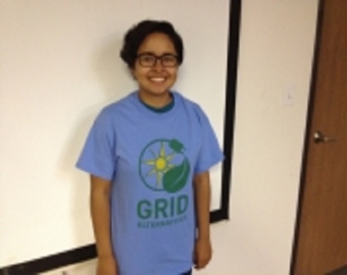 Teen wearing blue GRID shirt with sun and leaf logo, smiling at camera