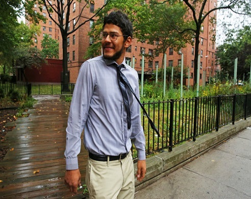 Man in light blue shirt and khaki pants standing in urban garden courtyard