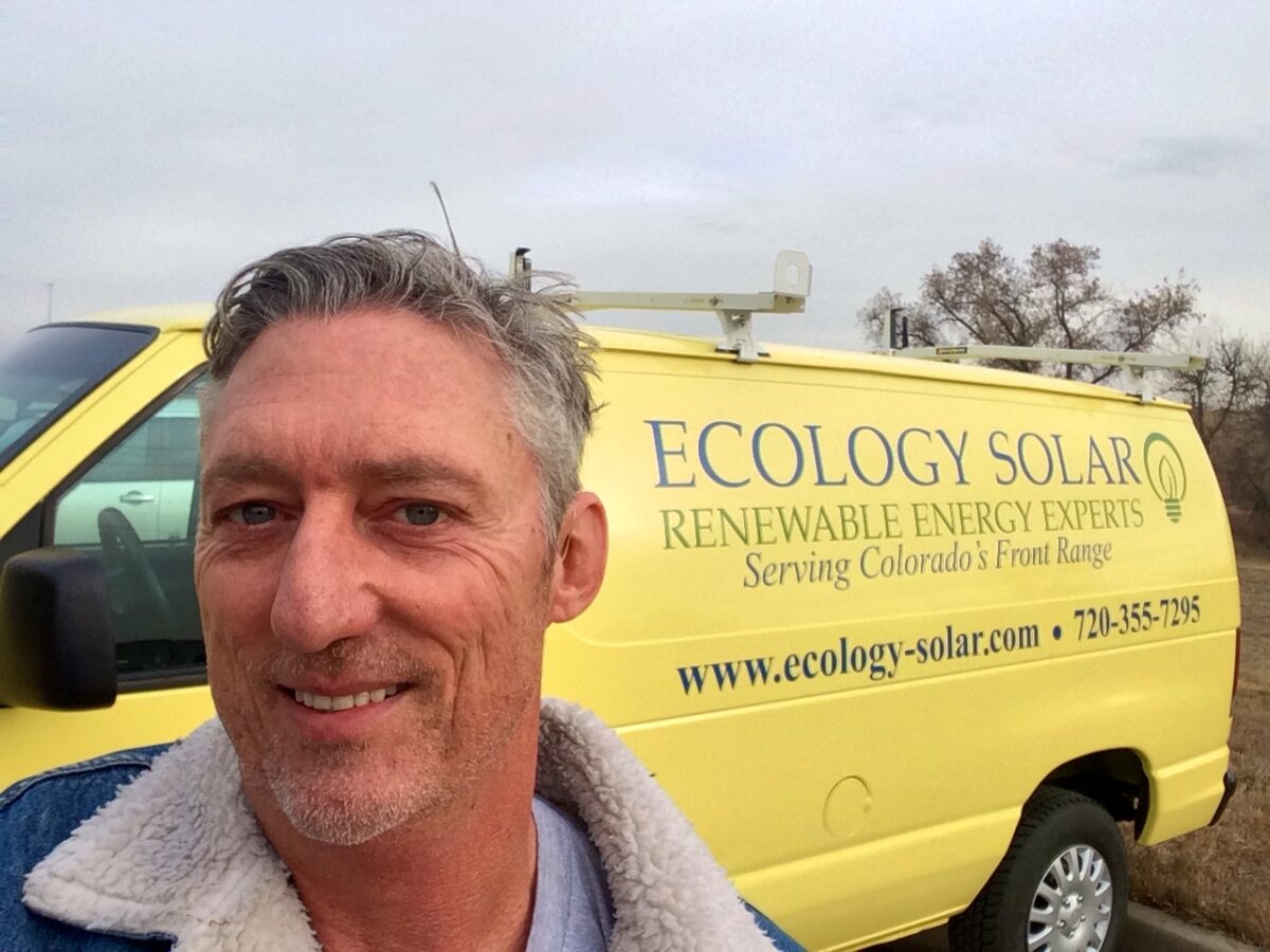 Man smiling next to yellow Ecology Solar van in Colorado Front Range