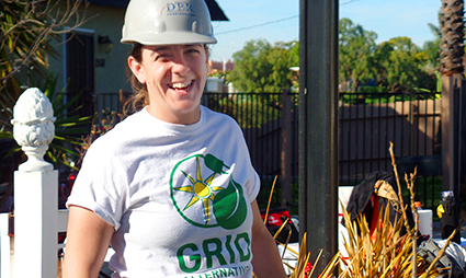 Man in hard hat wearing GRID shirt smiles at outdoor construction site