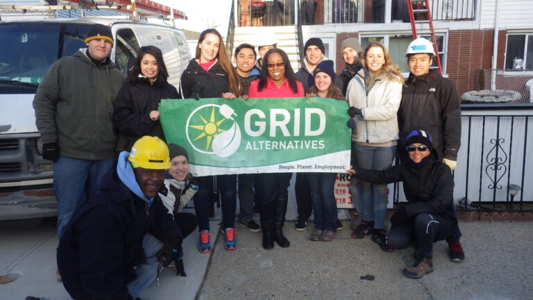 Group of volunteers holding GRID Alternatives banner with tagline "People. Planet. Employment