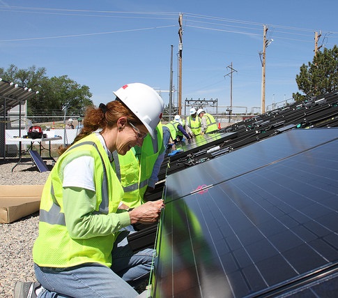 Worker in safety gear inspecting solar panels at an installation site