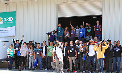 Large group of diverse students and adults posing together outside a building with a GRID banner visible