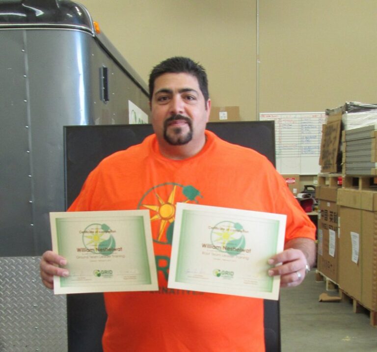 Man in orange shirt holding two solar energy certificates in warehouse setting