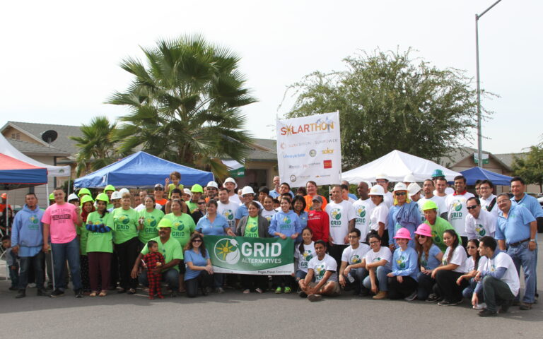 Large group of GRID Alternatives volunteers at 2015 Central Valley Solarthon event with banners and tents