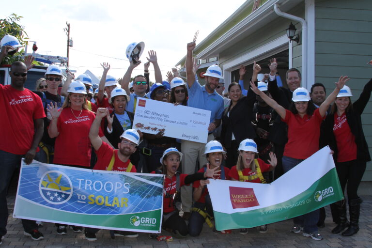 Group of volunteers in hard hats celebrating Troops to Solar initiative with Wells Fargo donation check
