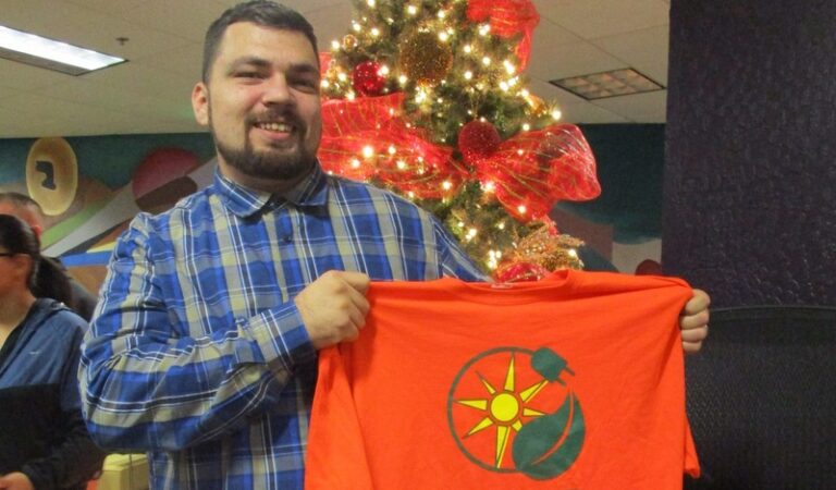 Man holding red flag with sun and circle design at holiday event