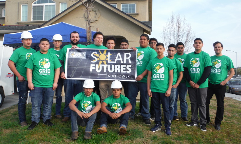 Group of students in green GRID shirts holding "Solar Futures Sunpower" banner at a community service event