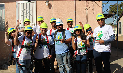 Group of Sunrun employees wearing yellow hard hats and volunteer shirts at a community service event in South Los Angeles