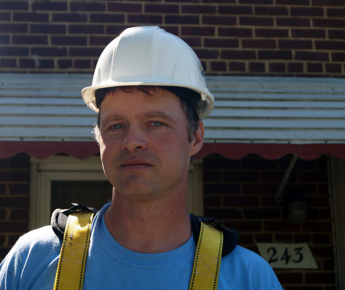 Construction worker wearing white hard hat and yellow safety vest on job site