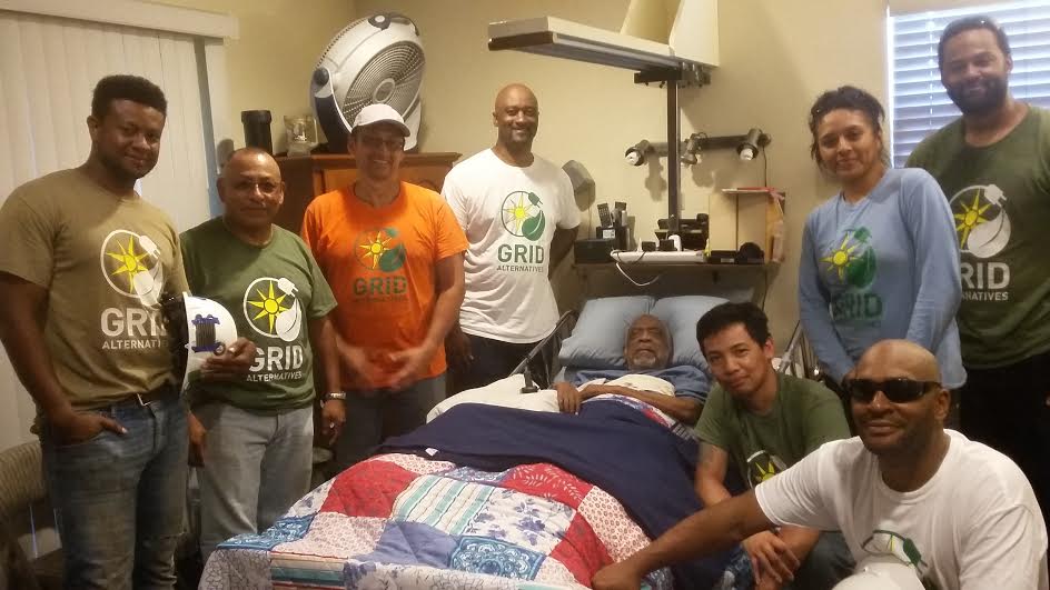 Group of volunteers wearing GRID Alternatives shirts visiting a man in his home
