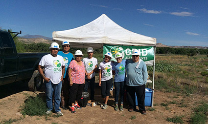 Group of people in hard hats gathered under white tent at solar project site in rural area