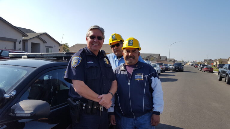Police officer and construction workers shaking hands on a residential street during community event