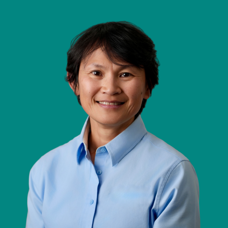 Bambi Tran, smiling woman in light blue button-up shirt against teal background