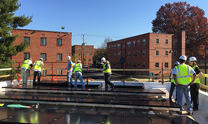 Construction workers installing solar panels on multifamily residential building roof