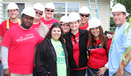 Group of volunteers in red shirts and hard hats at a construction site, thanking Wells Fargo