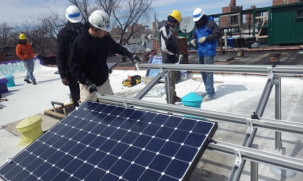Workers in hard hats installing solar panels on a residential building rooftop