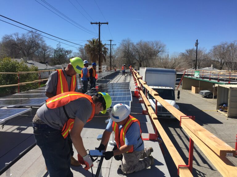 Workers in safety vests install solar panels on a residential rooftop during construction
