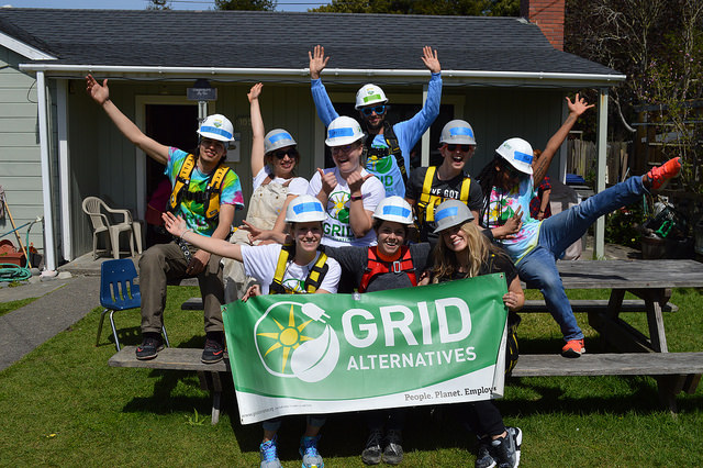 Group of volunteers in hard hats holding GRID Alternatives banner at Camp Solar event