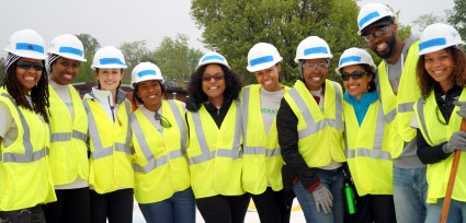 Group of construction workers in safety vests and hard hats smiling outdoors