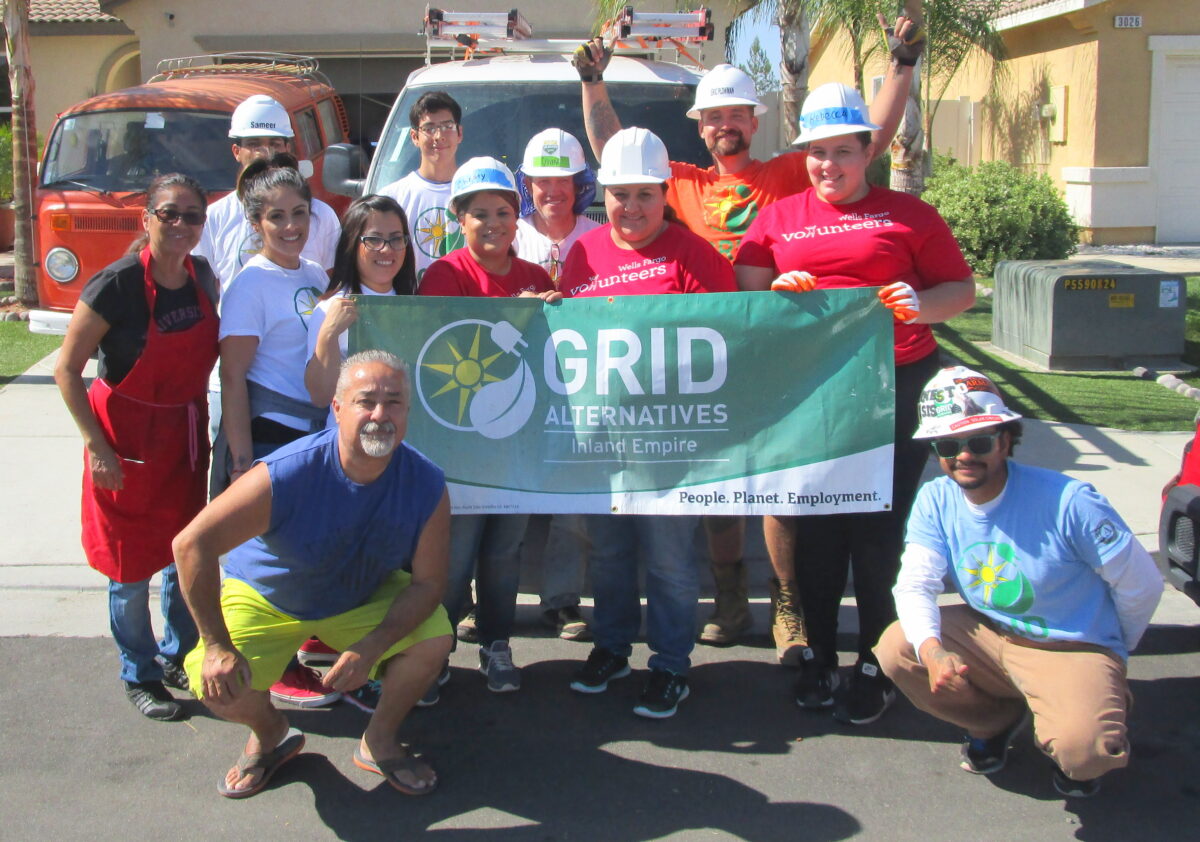 Group of volunteers holding GRID Alternatives Inland Empire banner at residential construction site