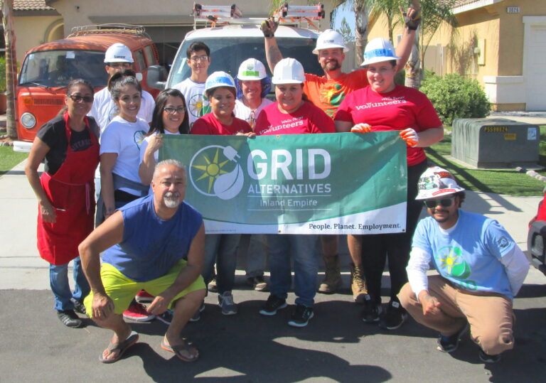 Group of volunteers holding GRID Alternatives Inland Empire banner at residential construction site