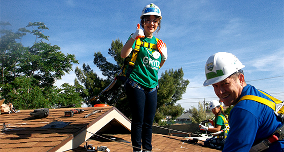 Two workers in safety gear installing solar panels on a residential roof