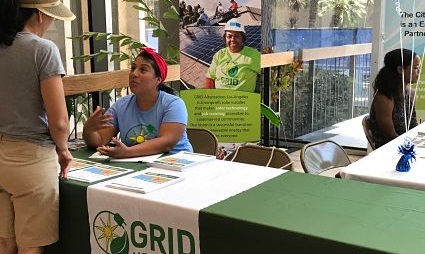 GRID staff members at community outreach table with informational materials and signage
