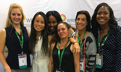 Six women wearing conference badges smile together at a solar industry event