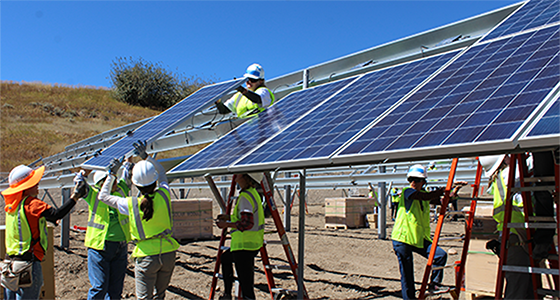 Workers in safety gear installing solar panels on a residential rooftop structure