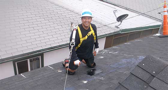 Worker in safety gear and harness on a rooftop during construction or maintenance work