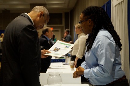 Man in suit handing pamphlet to woman at Solar Focus Job Fair 2017 table