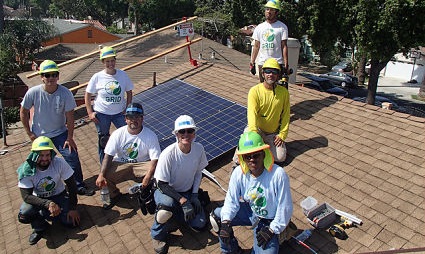 Team of workers installing solar panels on residential rooftop during community project
