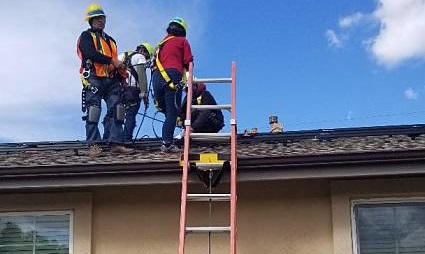 Construction workers in safety gear installing solar panels on a residential roof