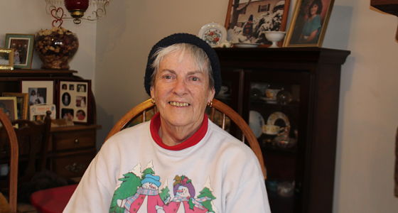 Smiling woman wearing festive sweater in living room with holiday decorations