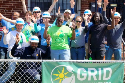 Group of volunteers in hard hats celebrating at a GRID construction event