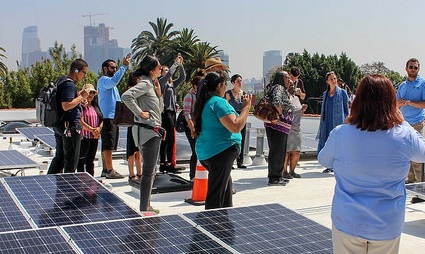 Group gathered on rooftop with solar panels and city skyline visible in background
