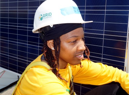 Worker in yellow jacket and GRID hard hat installing solar panels