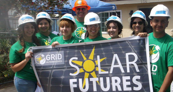 Group of nine people in hard hats and green shirts holding "Solar Futures" banner