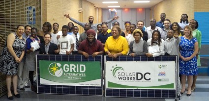 Large group of people posing with GRID and Solar Works DC banners at a workforce event