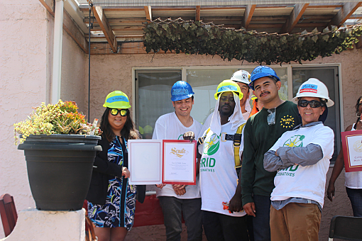 Group of people in hard hats holding a certificate at a home installation event