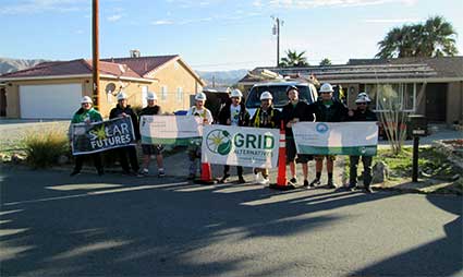 Community group holding signs at a neighborhood event, including banners for "GRID" and "Scholar's
