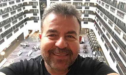 Man taking selfie from high-rise apartment balcony overlooking courtyard