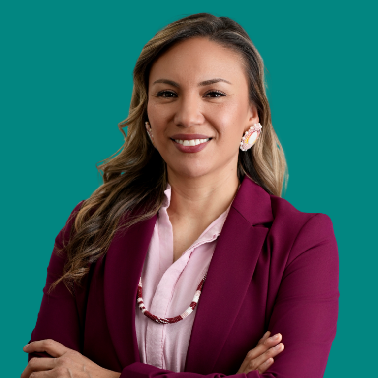 Professional headshot of Tanksi Clairmont wearing maroon blazer against teal background
