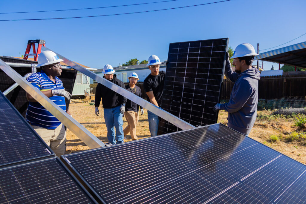 Group of workers in hard hats installing solar panels at an outdoor construction site