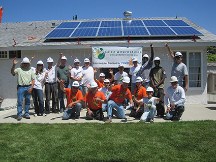 Group photo of GRID Alternatives volunteers and staff at solar panel installation on residential rooftop