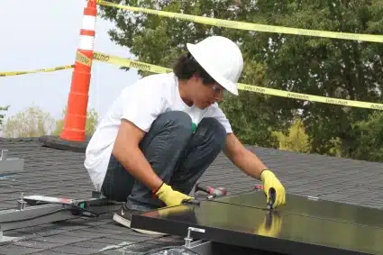 A tribal worker in hard hat adjusts panels for the solar PV system